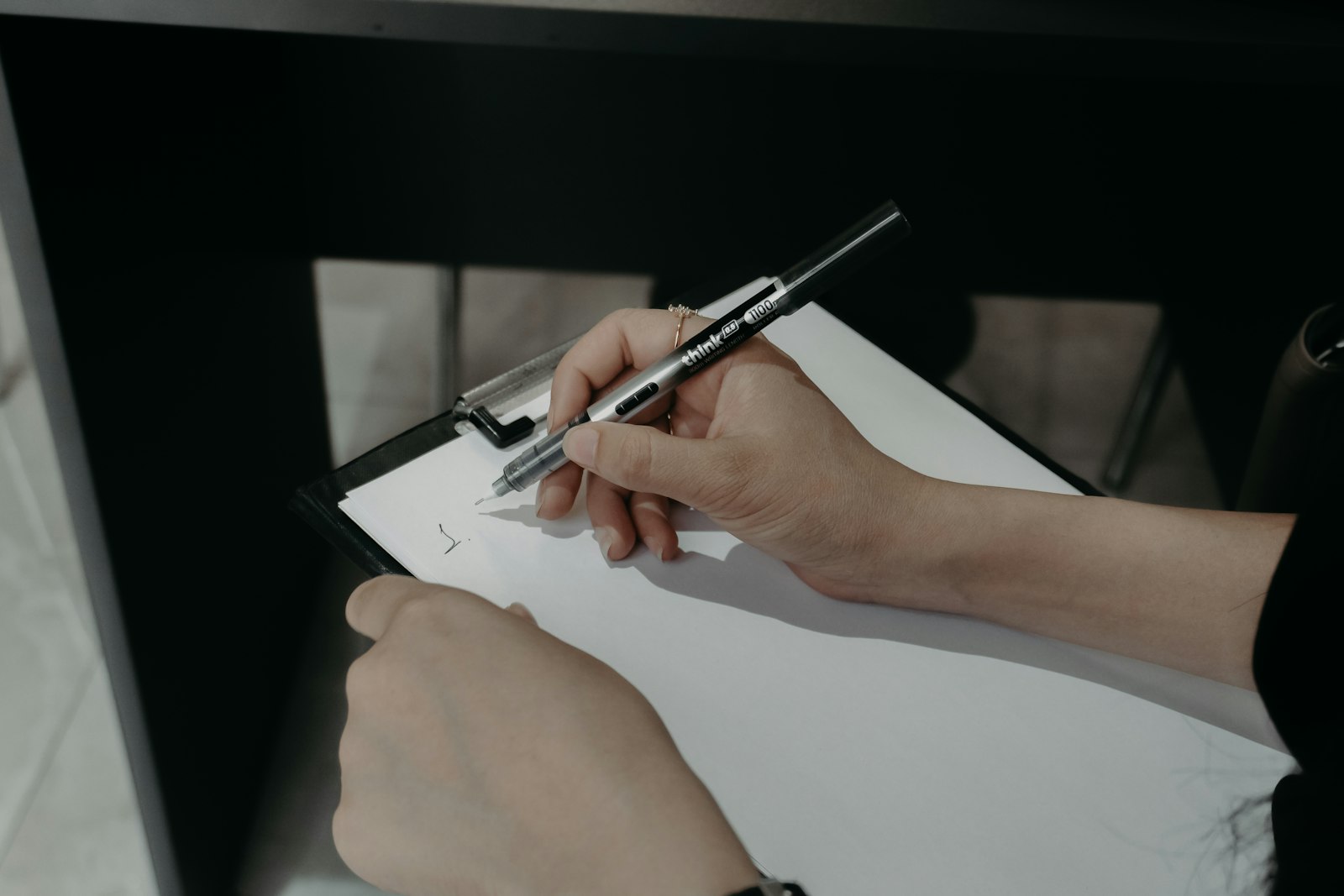 Hand hält einen Stift über einem Klemmbrett mit Protokollbogen
